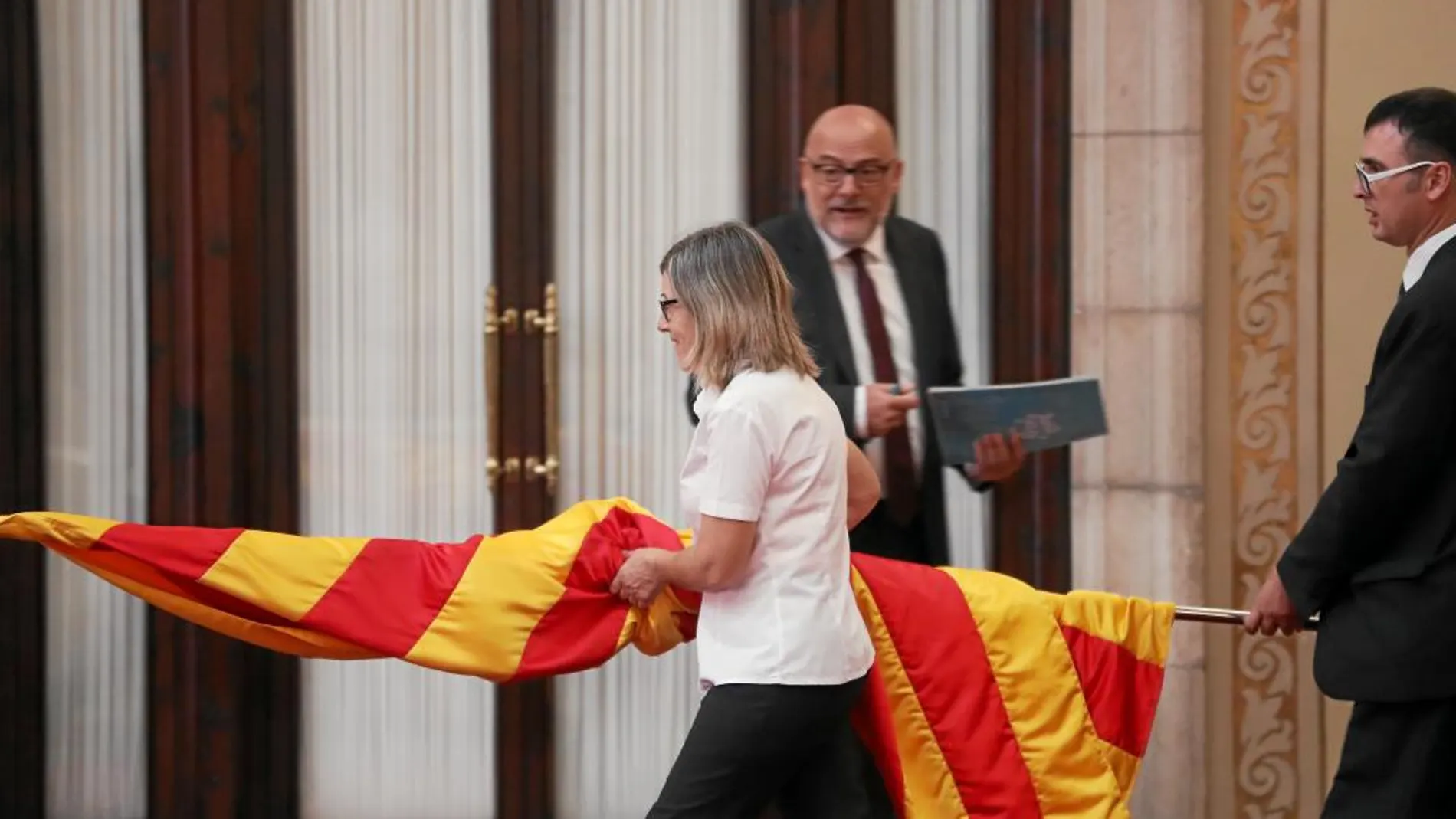 Miembros del parlamento catalán colocan la bandera catalana antes del inicio de la sesión parlamentaria