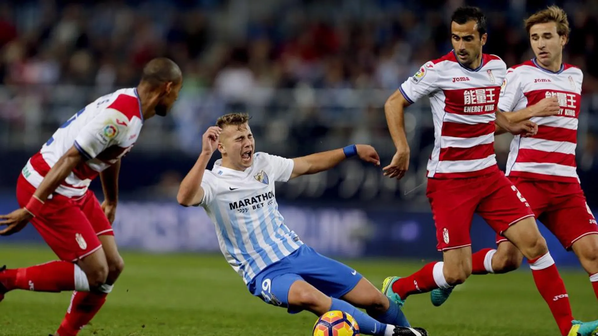 El centrocampista del Málaga CF Javier Ontiveros (2i) cae ante los jugadores del Granada CF, el defensa brasileño Gabriel Silva (i), el defensa francés Matthieu Saunier (2d) y el centrocampista Sergi Samper