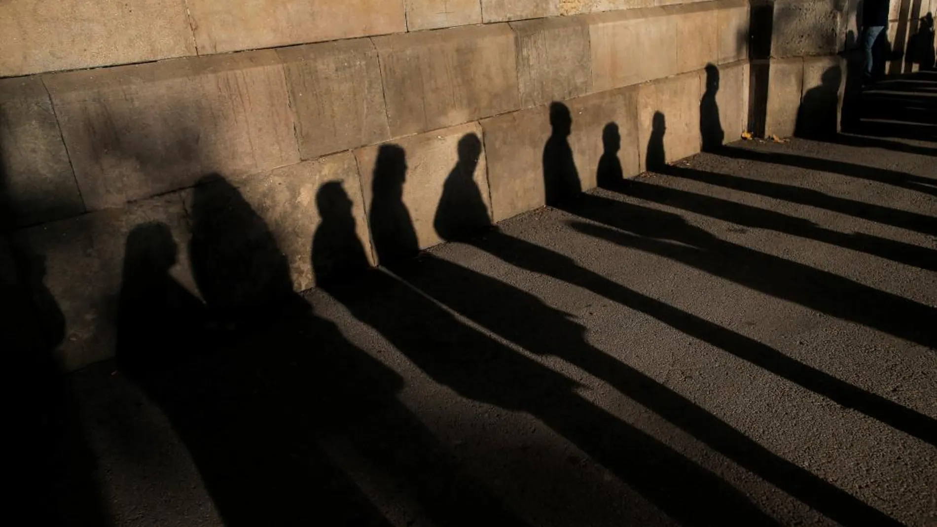Sombras de votantes que hacen fila frente a un colegio electoral de Barcelona para ejercer el derecho al voto en estas autonómicas