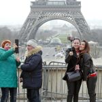 Turistas con sus móviles ante la torre Eiffel de París