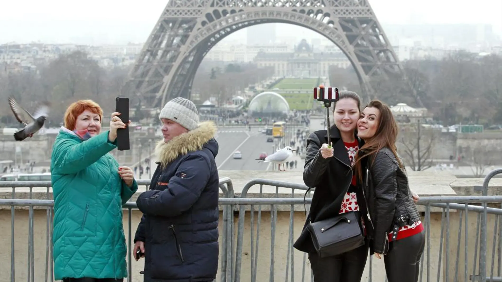 Turistas con sus móviles ante la torre Eiffel de París
