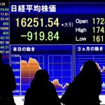 Varios viandantes pasan delante de una pantalla que muestra información bursátil en Tokio