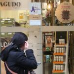 Una mujer pasa frente a una farmacia de Valladolid con el cartel que anuncia su incorporación al programa contra esta lacra social
