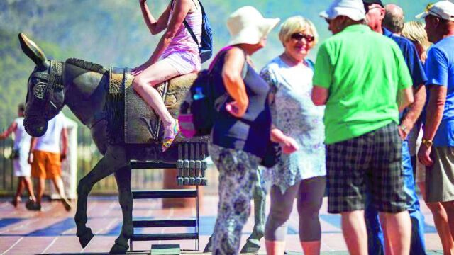 Una turista subida al monumento del burro-taxi en la localidad malagueña de Mijas.