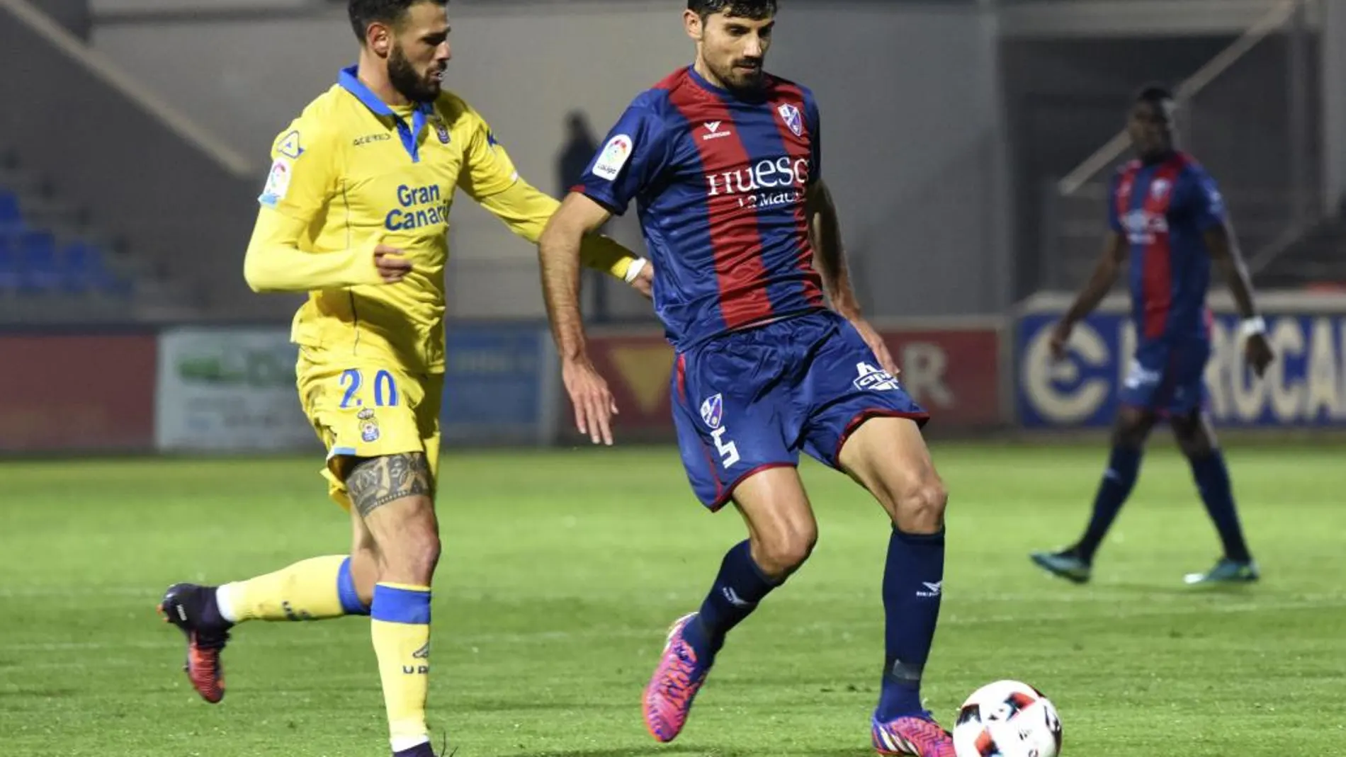 El centrocampista del Huesca Juan Aguilera (d) disputa un balón con el delantero Tyronne del Pino (i), de Las Palmas