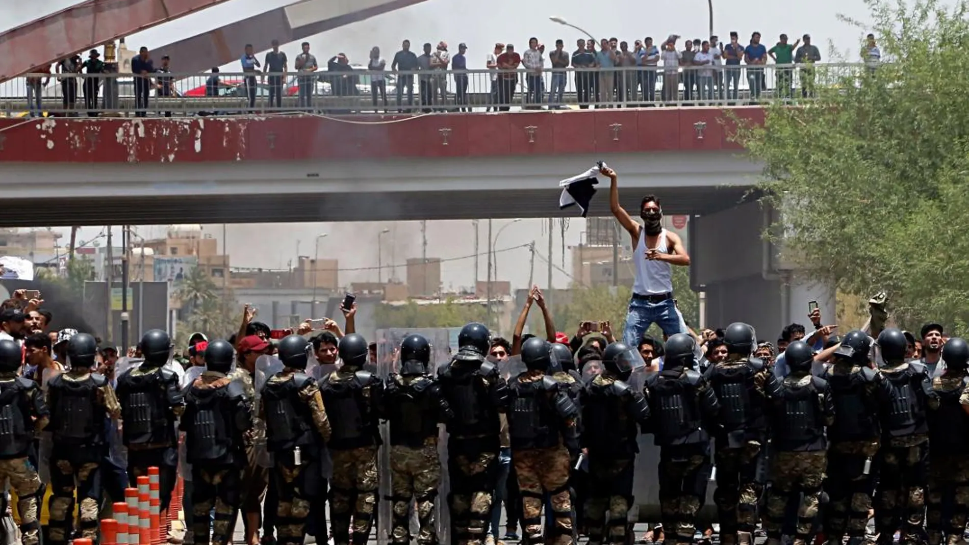 Policías frente a manifestantes durante una protesta en la ciudad iraquí de Basora para pedir mejores servicios públicos. (AP Photo)