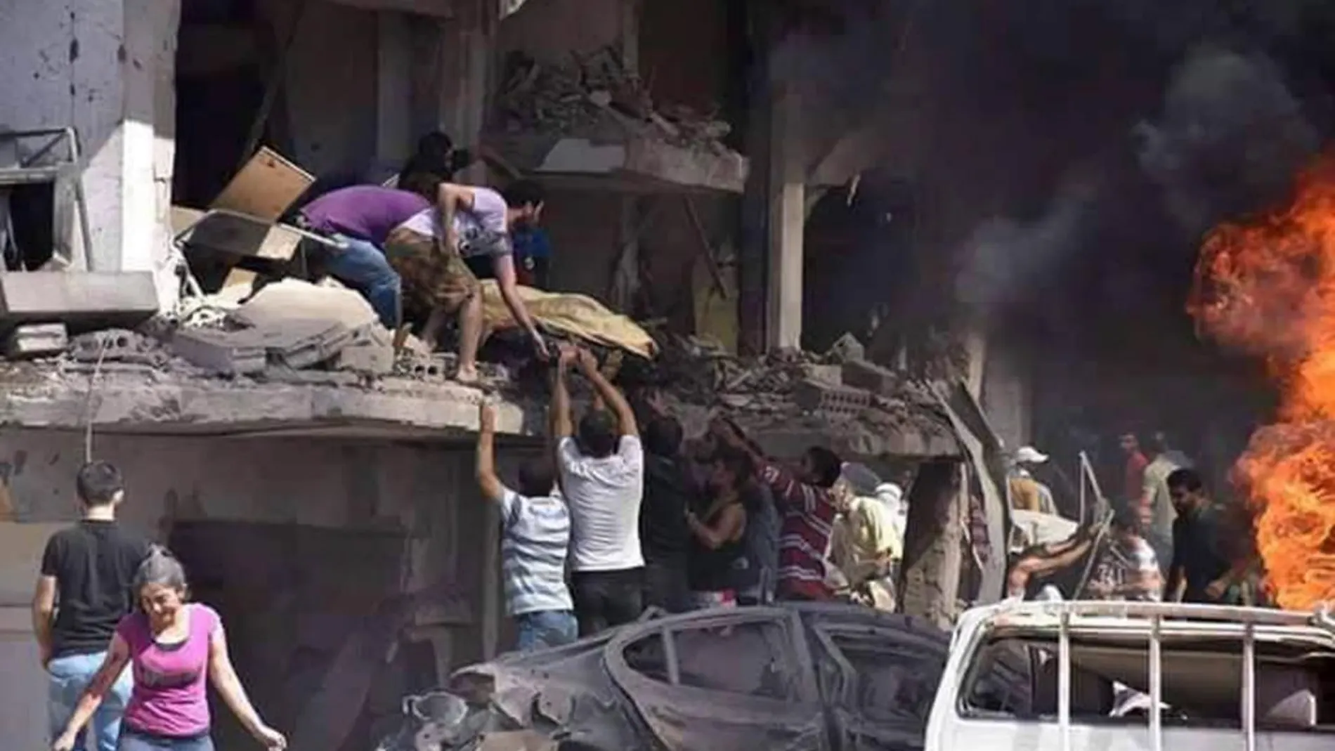 Fotografía facilitada por la Agencia Oficial de Noticias siria, SANA, que muestra a varias personas mientras trasladan un cuerpo tras la explosión de una bomba en Qameshli, Siria