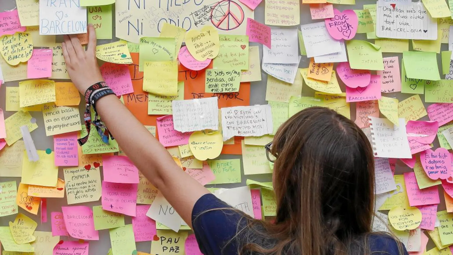Una mujer deja una nota con un mensaje de apoyo en Las Ramblas de Barcelona, que poco a poco vuelven a la normalidad