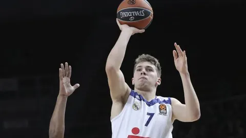 El jugador del Real Madrid Luka Doncic (dcha) tira a canasta sobre la defensa de Bryant Dunston (izq), del Anadolu Efes