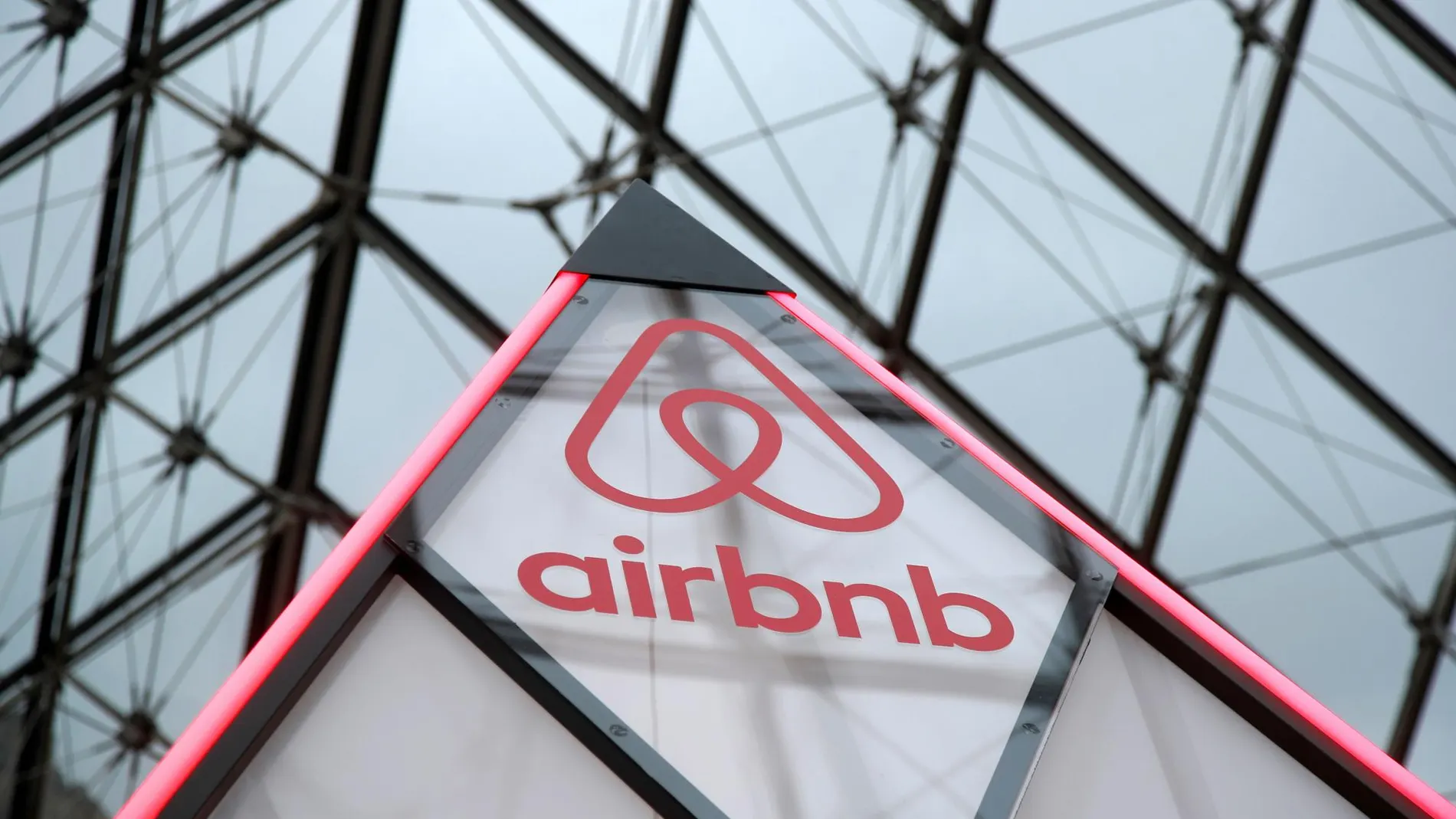 El logo de Airbnb, junto a la piramide de El Louvre