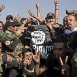 Soldaos iraquíes y kurdos con una bandera arrabatada al Estado Islámico en Bartella