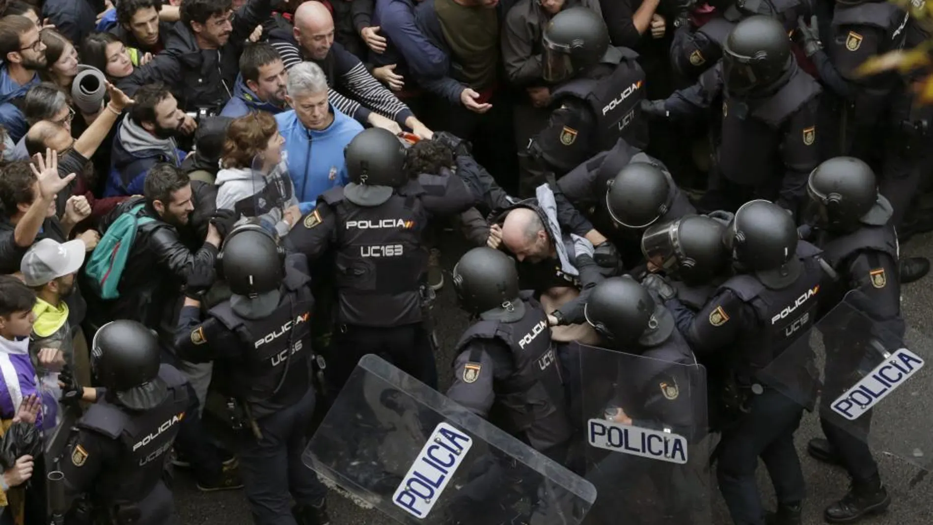 Agentes antidisturbios de la Policía Nacional forman un cordón de seguridad frente al colegio Ramón Llull de Barcelona