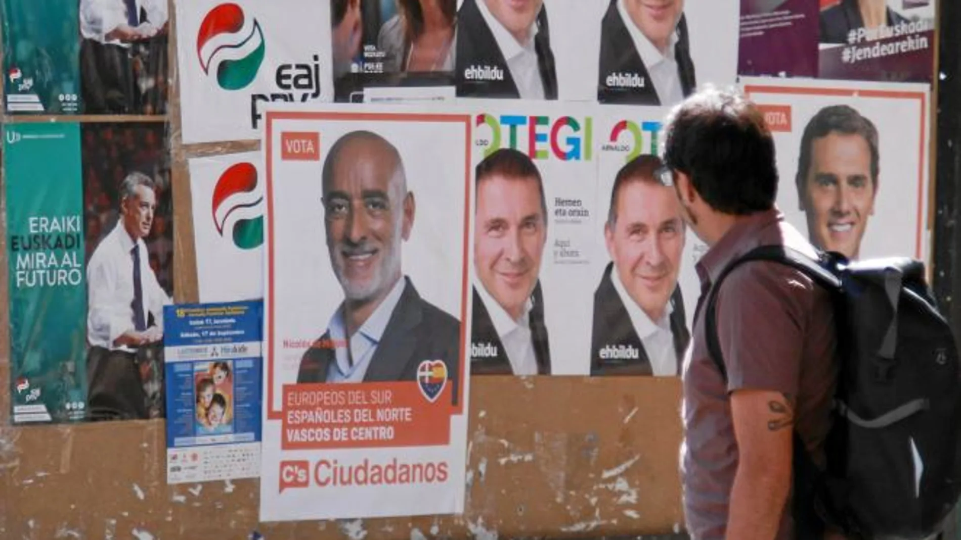 Un ciudadano observa ayer en Bilbao los carteles de la campaña a las elecciones autonómicas