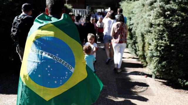 Un brasileño envuelto en una bandera a la puerta de la Casa de Brasil en Madrid después de votar. EFE