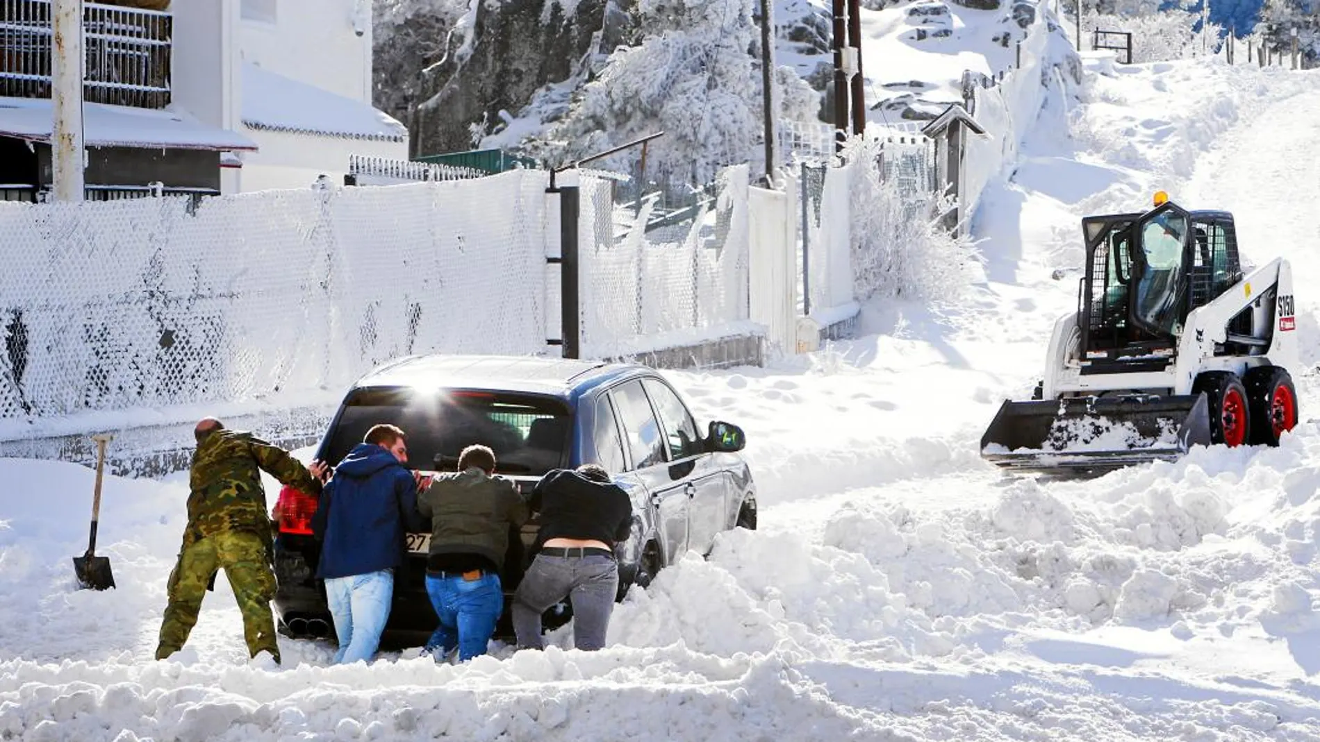 Varias personas tratan de sacar un coche atrapado en la nieve, ayer, en el puerto de Guadarrama