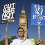 Un hombre sostiene pancartas con consignas en contra del uso de las armas nucleares durante una manifestación delante de la Cámara de los Comunes en Londres, Reino Unido