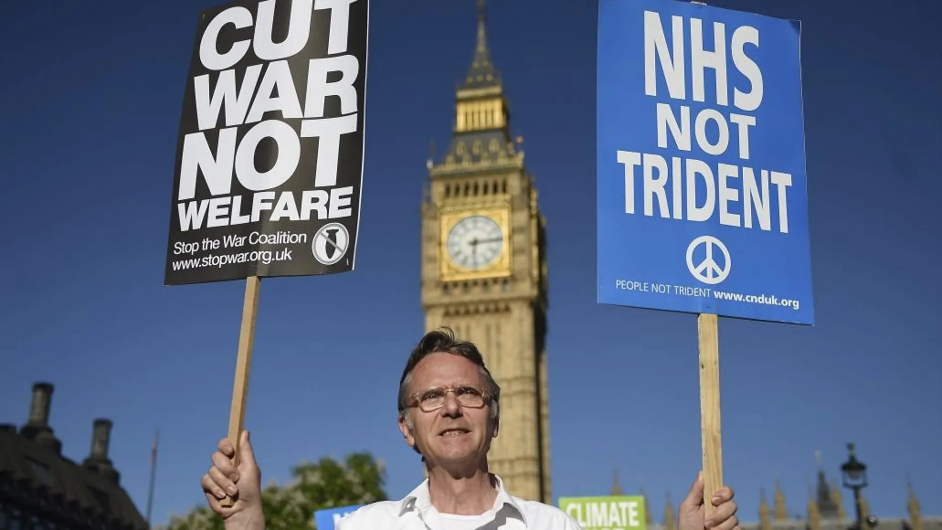 Un hombre sostiene pancartas con consignas en contra del uso de las armas nucleares durante una manifestación delante de la Cámara de los Comunes en Londres, Reino Unido