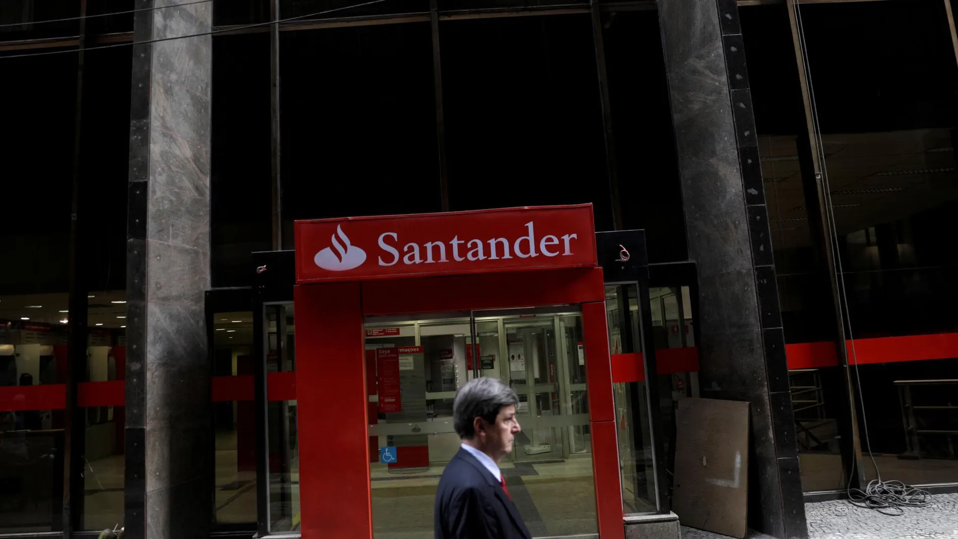 Un hombre camina frente a una oficina de Banco Santander en Río de Janeiro
