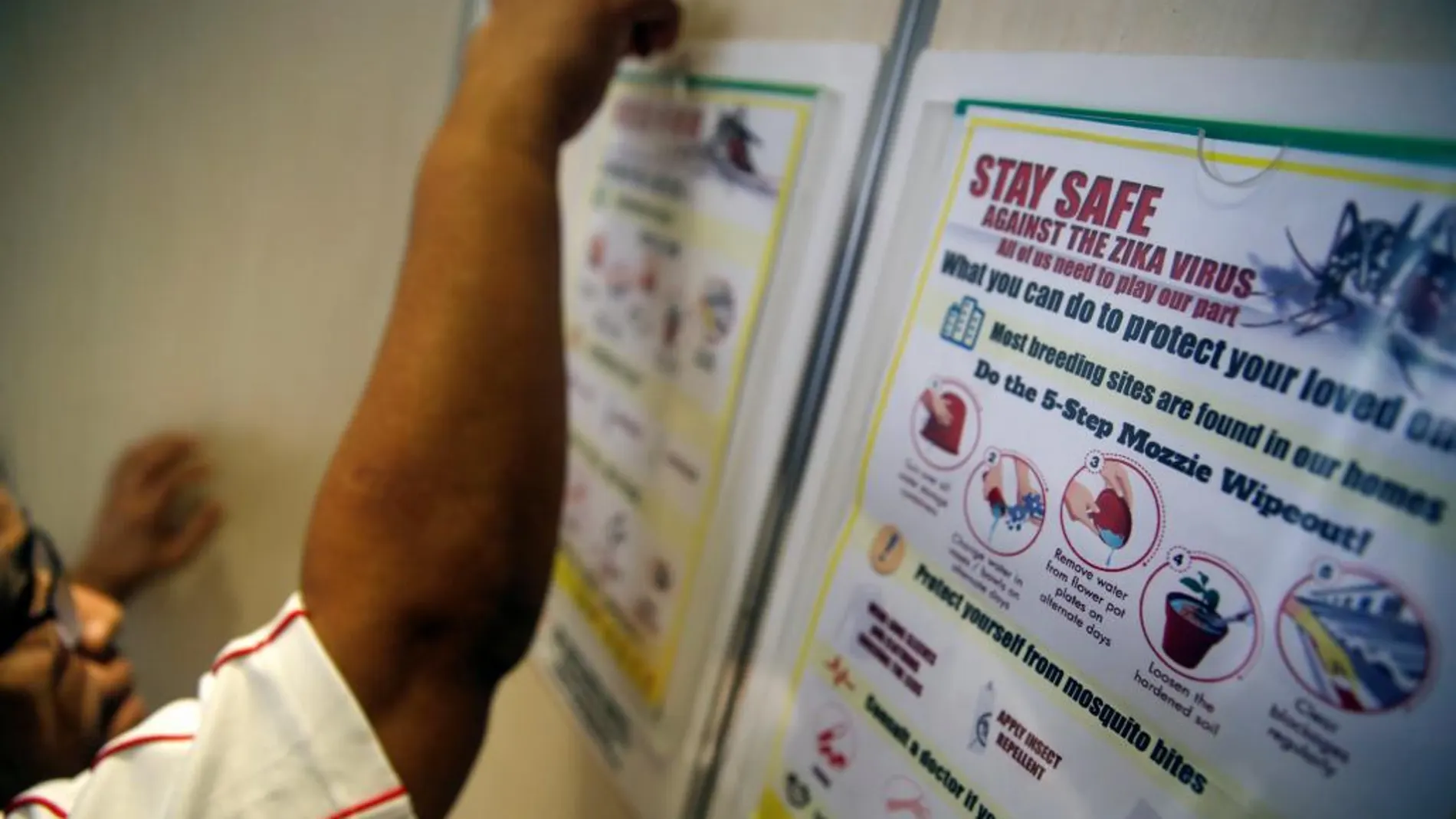 Un voluntario cuelga un cartel informativo sobre el zika en Singapur
