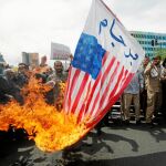 Un grupo de manifestantes iraníes quema banderas de EE UU y carteles de Trump en Teherán, ayer