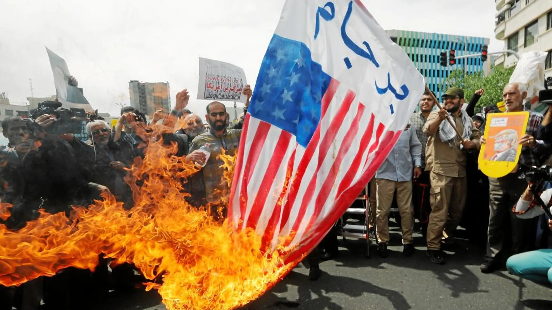 Un grupo de manifestantes iraníes quema banderas de EE UU y carteles de Trump en Teherán, ayer