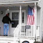 Un activista deja carteles en las casas de Lawrence para animar a votar