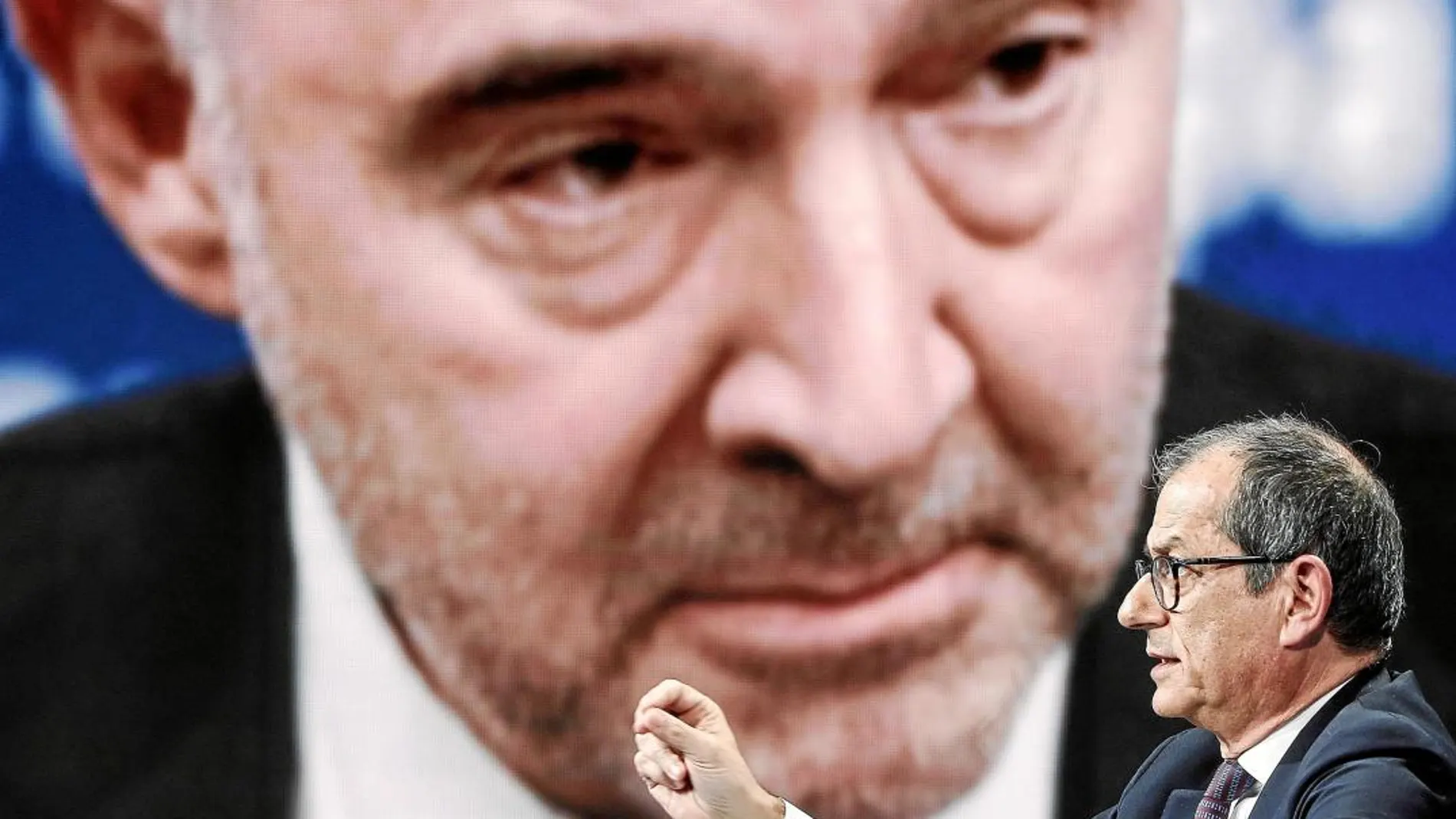 El ministro de Economía y Finanzas italiano, Giovanni Tria. De fondo, una imagen del comisario europeo, Pierre Moscovici