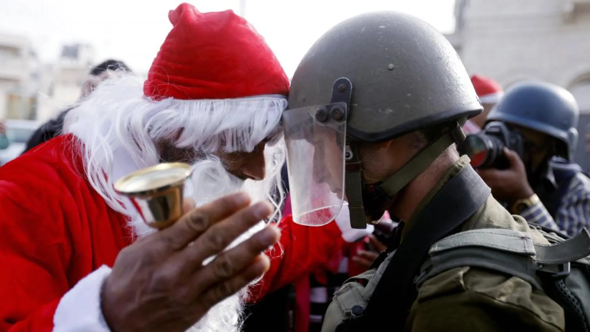 Un manifestante palestino vestido de Santa Claus se encara a un soldado israelí, ayer, en Belén