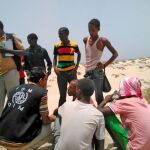 Un trabajador de la Organización Internacional para las Migraciones ayuda a migrantes somalíes y etíopes que fueron obligados a arrojarse al mar en una playa de Yemen