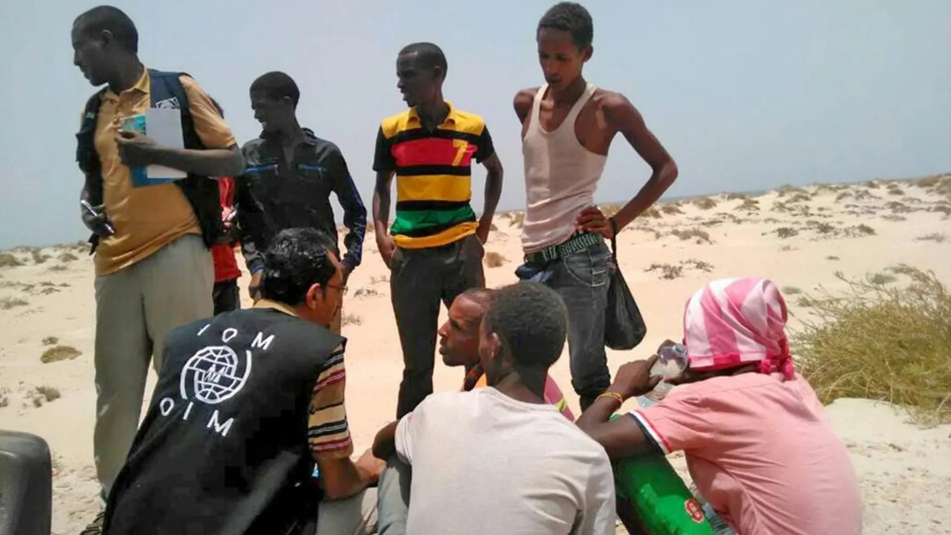 Un trabajador de la Organización Internacional para las Migraciones ayuda a migrantes somalíes y etíopes que fueron obligados a arrojarse al mar en una playa de Yemen
