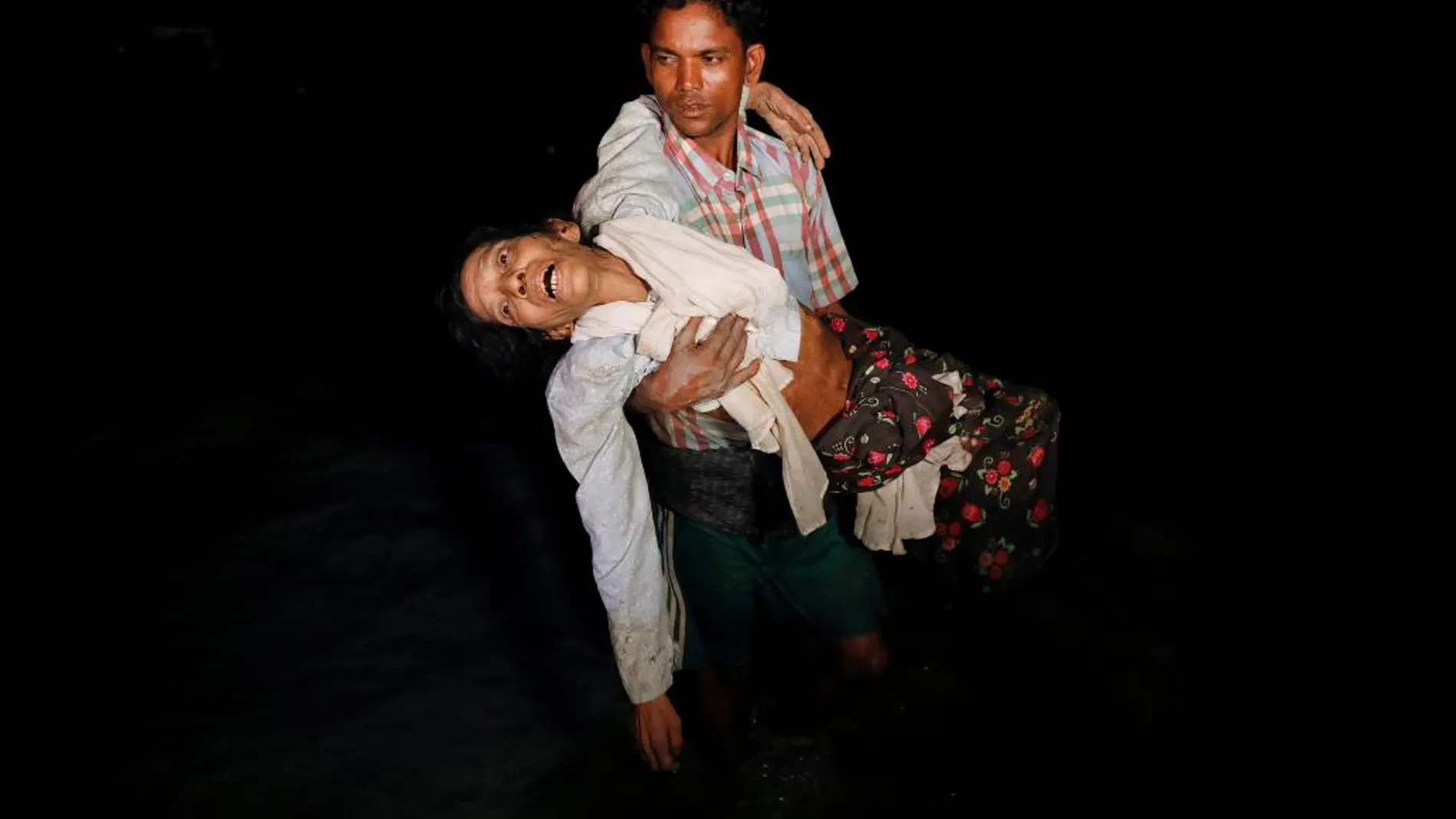 Un hombre carga con su mujer a su llegada a Myanmar