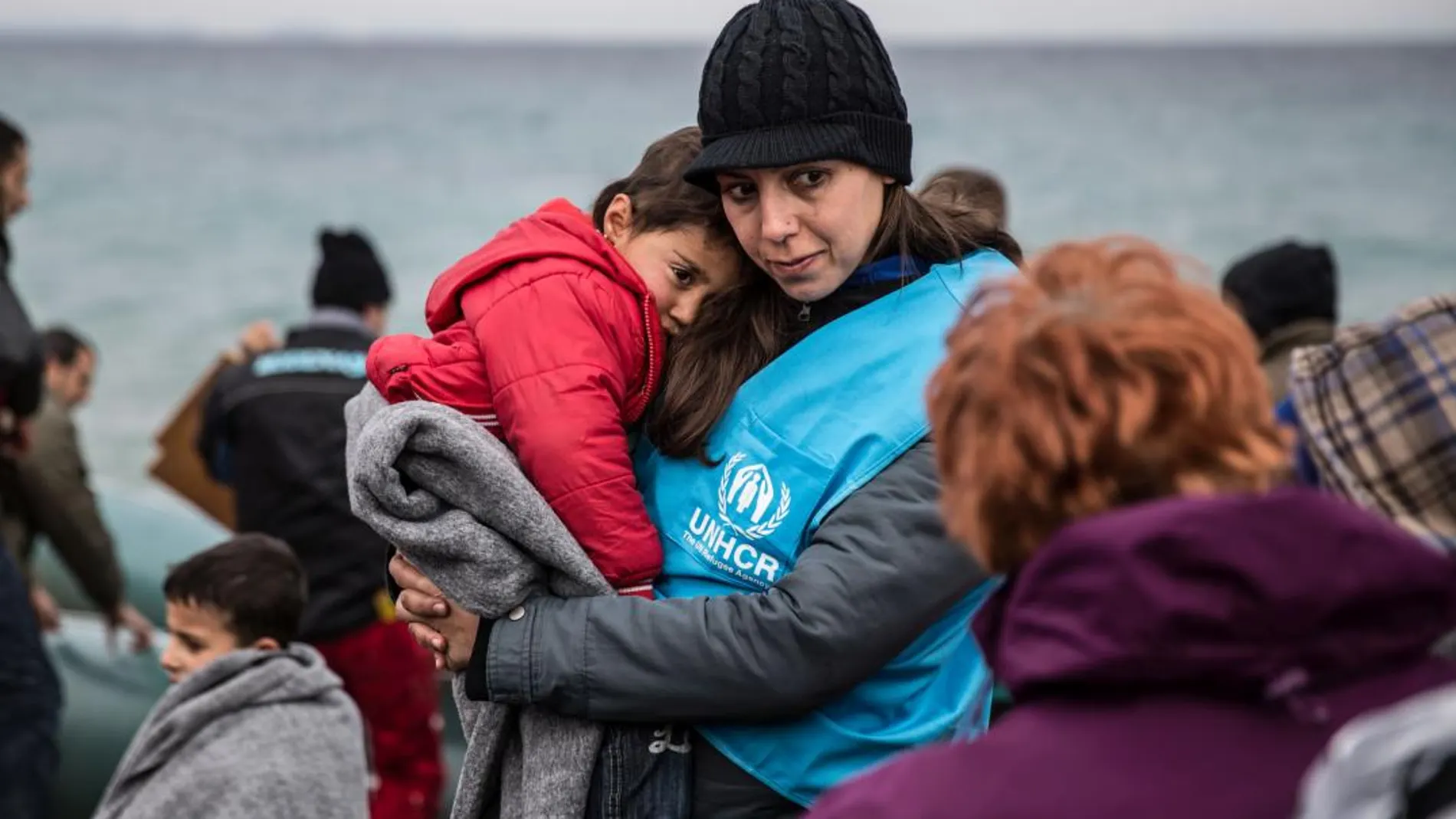 Una trabajadora de ACNUR da calor a un niño refugiado tras llegar en bote a la isla griega de Lesbos