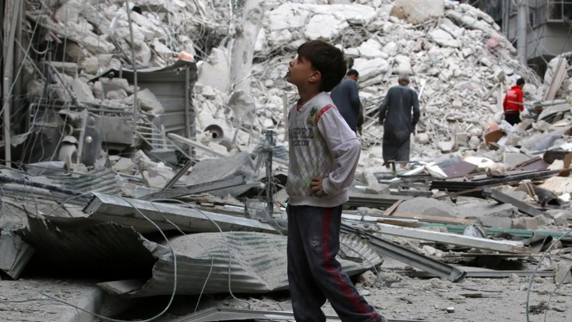 Un niño inspecciona un sitio dañado después de los ataques aéreos