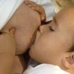 Una madre embarazada dando el pecho a su hijo de dos años