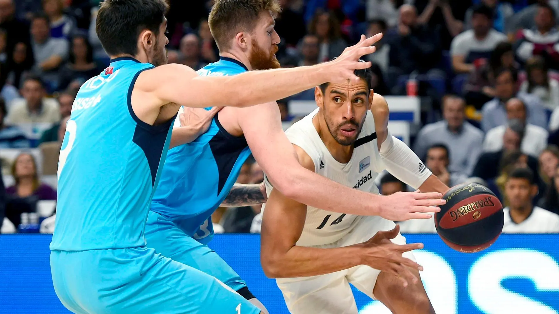 El pívot del Real Madrid Gustavo Ayón (d) avanza ante el estadounidense Shayne Whittington (c) y Brizuela, anbos de Estudiantes