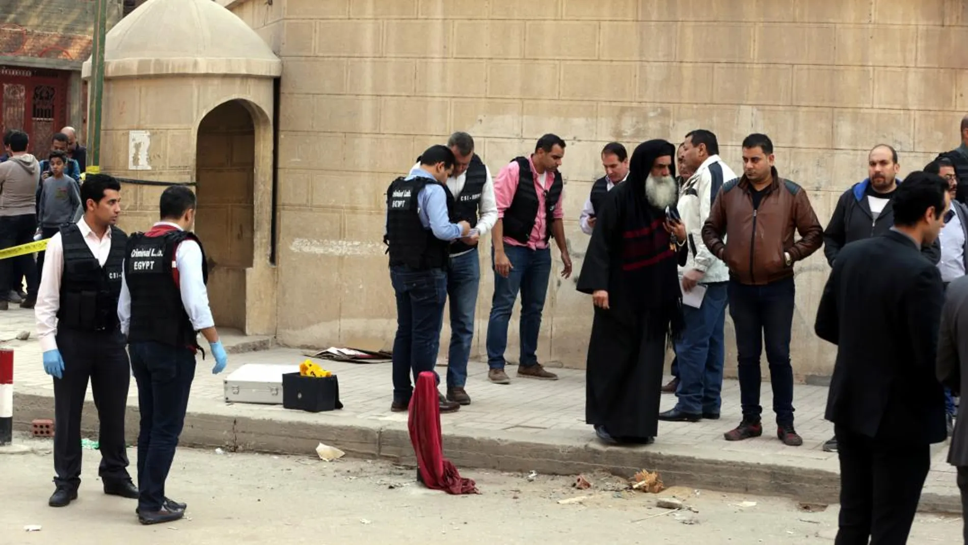 Miembros de las Fuerzas de Seguridad y curiosos congregados en los alrededores de la iglesia Mar Mina tras el ataque contra el templo en el distrito de Heluán, en el sureste de El Cairo