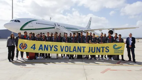 El Villarreal, con una pancarta por el cuarto aniversario de la apertura de vuelos comerciales en el aeropuerto de Castellón. Al fondo, su lujoso avión