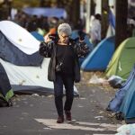 Una parisina pasea entre las tiendas de campaña de un campamento de migrantes en el distrito 19 de París