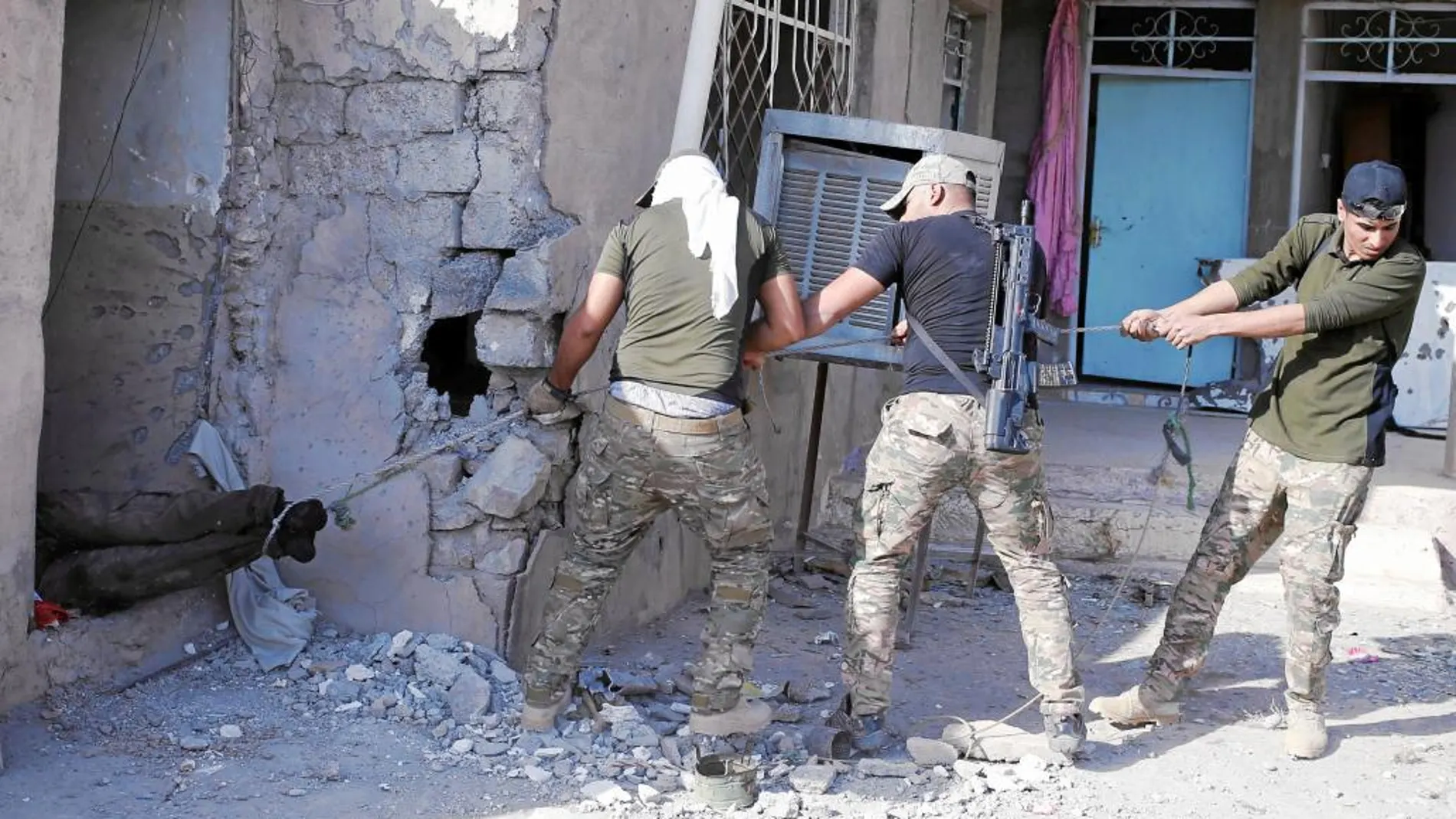 Las fuerzas especiales iraquíes arrastran el cadáver de un combatiente del EI cerca de Karamah, en Mosul, ayer