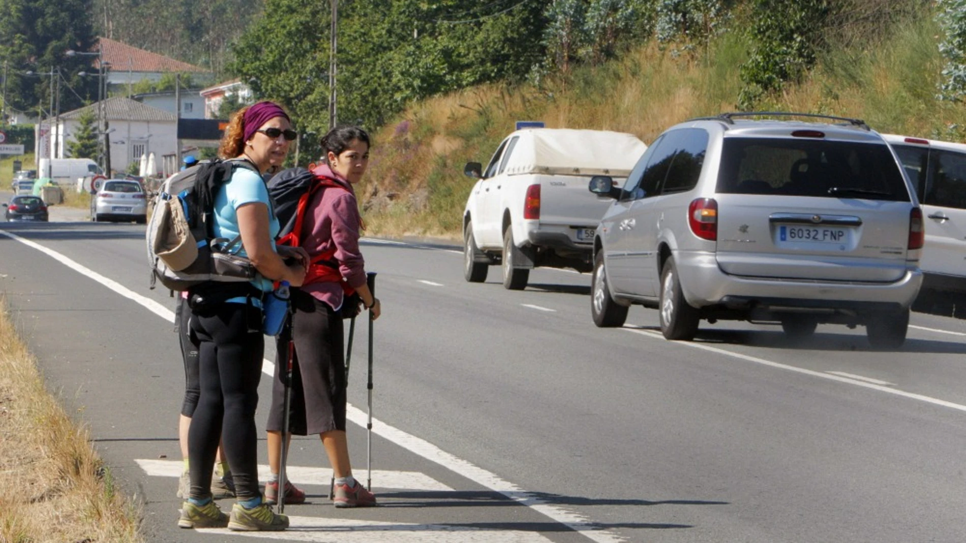 Unas peregrinas observan el tráfico en el camino de Santiago