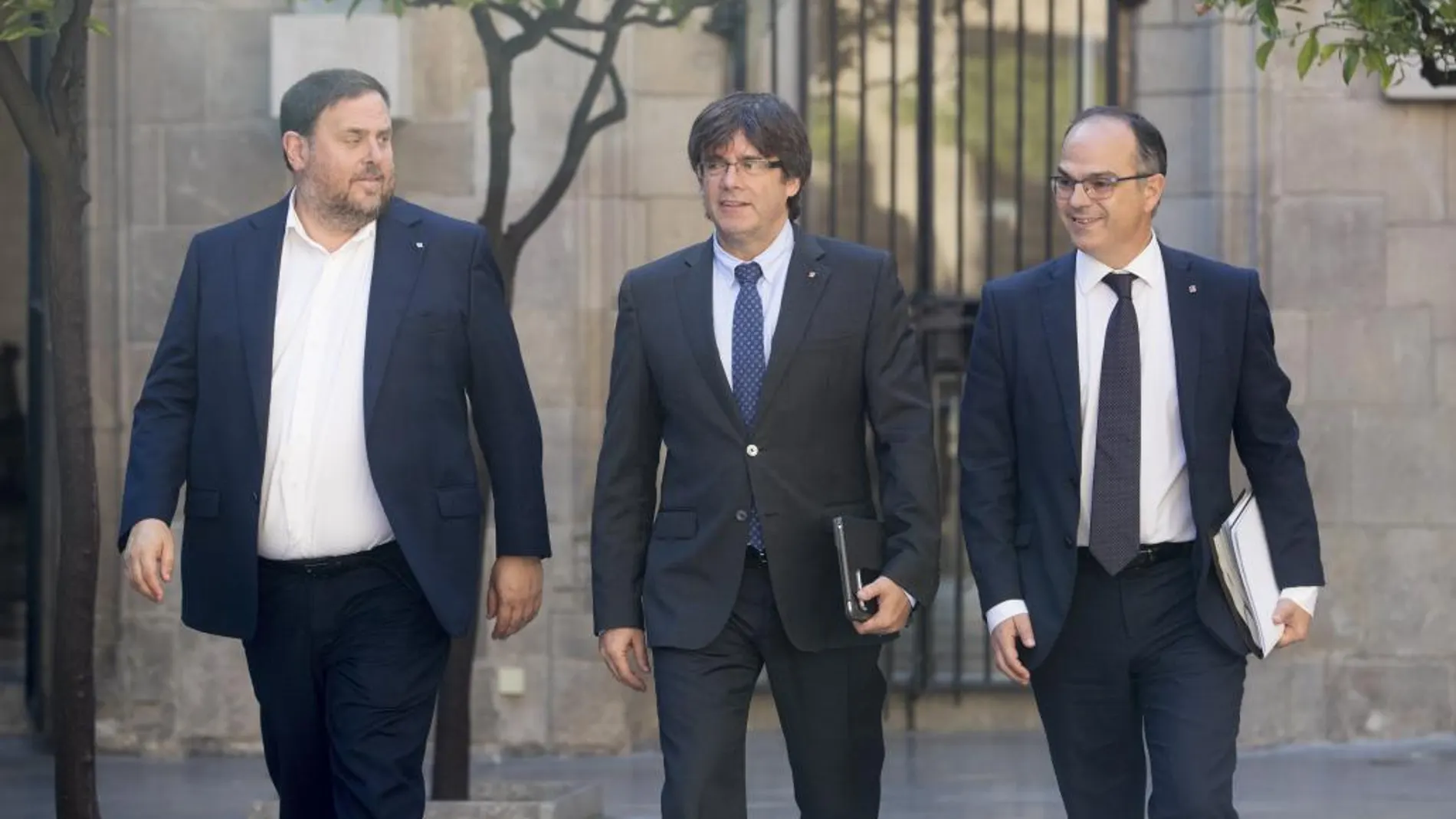 Carles Puigdemont junto a Oriol Junqueras y el conseller de la Presidencia, Jordi Turull (d), se dirigen hoy a la reunión semanal del Govern.
