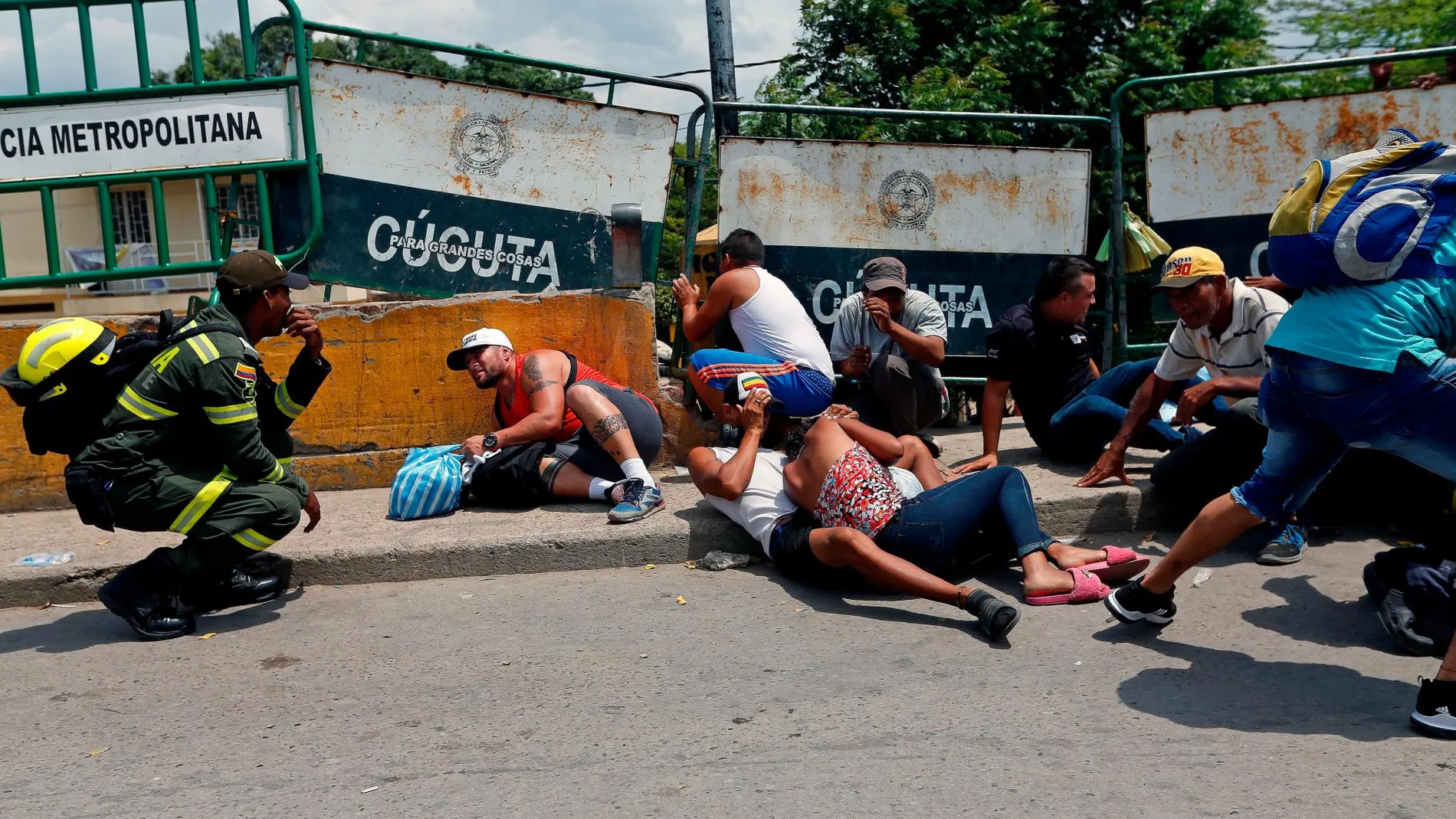 Un grupo de personas se protegen de los disparos en el puente internacional Simón Bolívar / Reuters