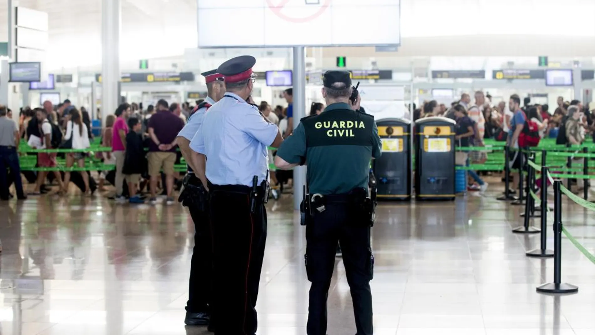 Agentes de la Guardia Civil se coordinan con los Mossos d'Esquadra (iz) en los alrededores de los accesos a las puertas de embarque en el aeropuerto de Barcelona