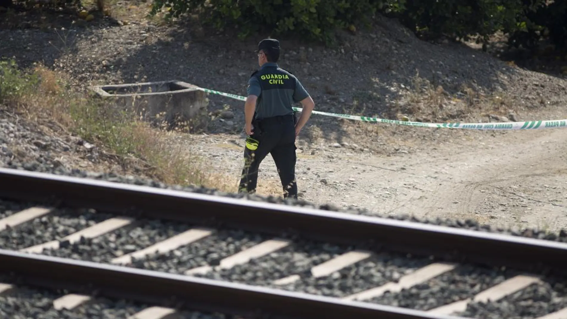 Un guardia civil inspecciona la zona acotada de la vía férrea que une la localidad malagueña de Álora con Málaga