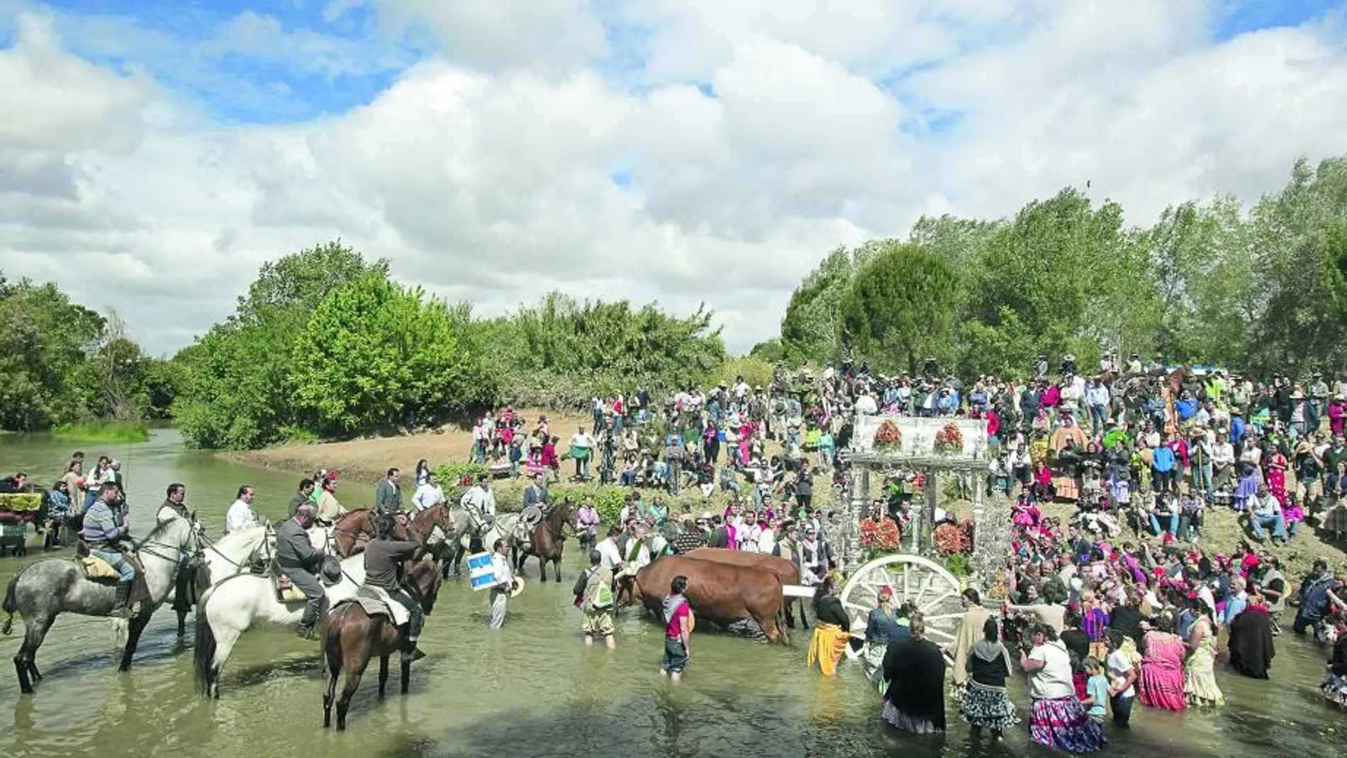La Hermandad de Sevilla Sur a su paso hoy por el Vado del Quema, paraje de la localidad sevillana de Aznalcázar, donde caballos, peregrinos y carros cruzan el río Guadiamar, testigo, romería a romería, del ingreso oficioso en la devoción de los nuevos romeros a través del "bautizo rociero".