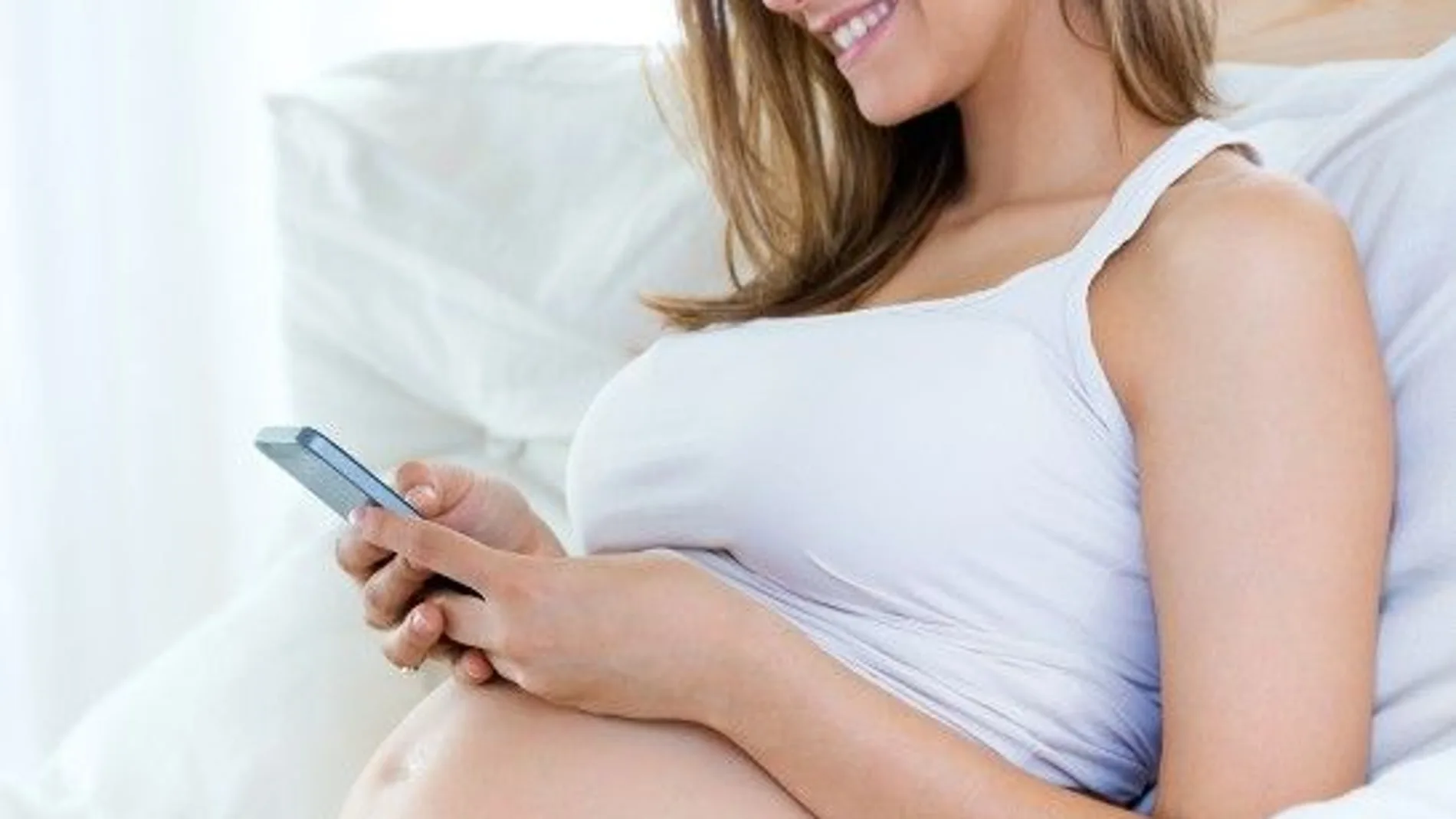 Una mujer embarazada usando el móvil