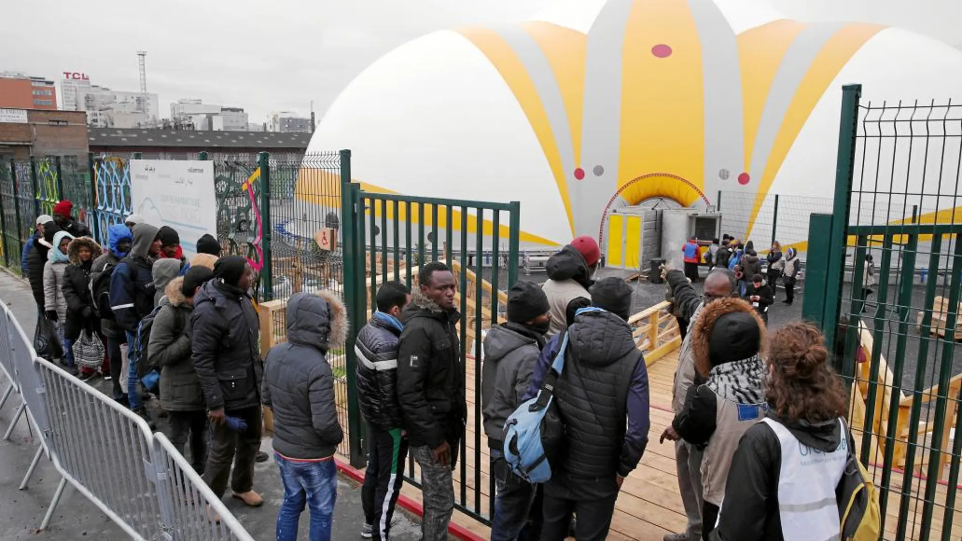 Migrantes acceden al centro de acogida que abrió sus puertas ayer en París y que puede acoger a 400 personas