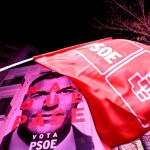 Una bandera del PSOE es ondeada con el cartel de la campaña electoral de Pedro Sánchez