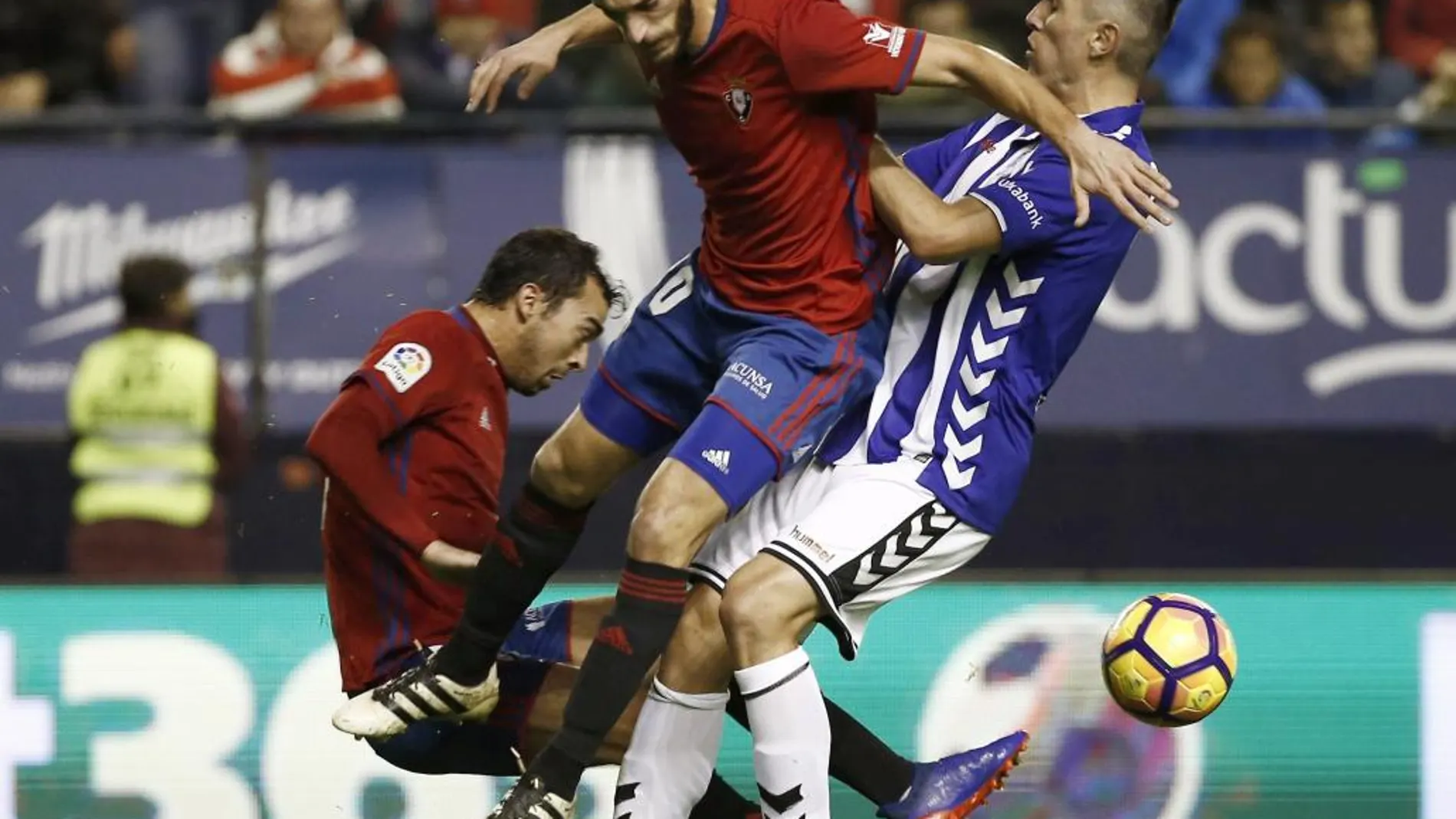 Los centrocampistas Miguel de las Cuevas y Roberto Torres, del Osasuna, intentan arrebatar el esférico al centrocampista del Deportivo Alavés, Víctor Camarasa