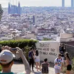 Unos turistas fotografían Barcelona junto a una pintada que se queja de su presencia: «Tu viaje de lujo, mi miseria diaria»